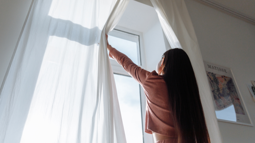 A woman opening the curtains revealing her new modern windows
