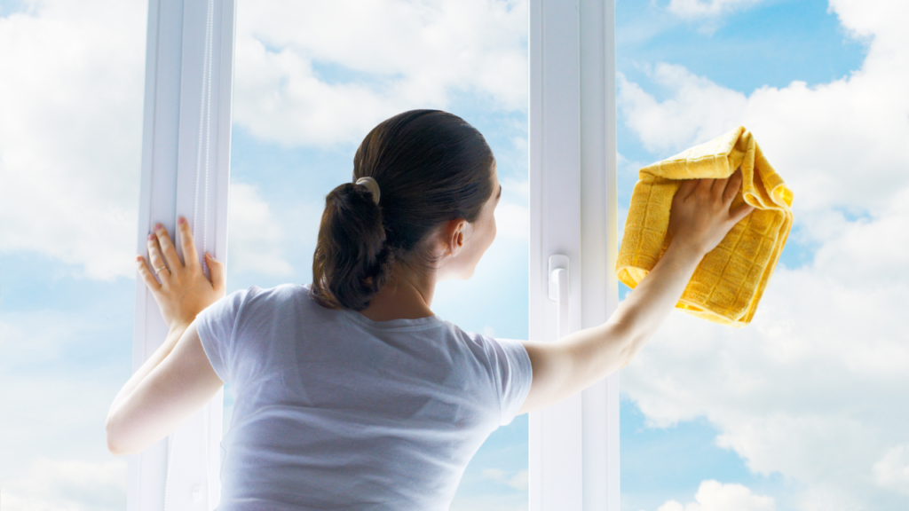 A woman wiping windows letting in natural light