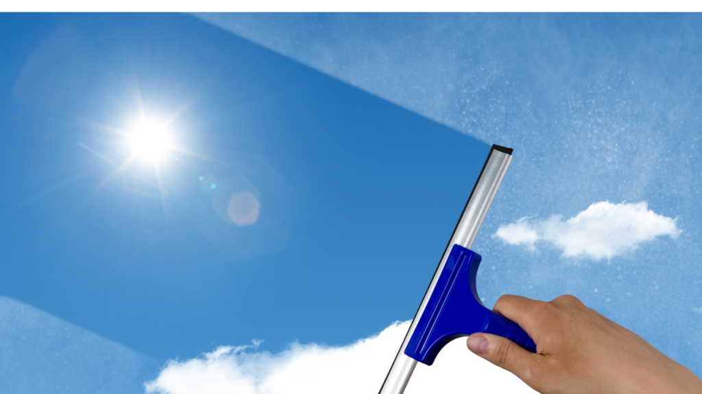 Cleaning a window with a squeegee with direct sunlight hitting the window glass