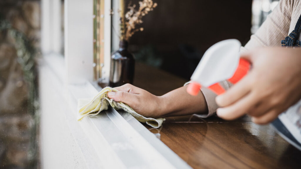 A person gently wipe a window sill